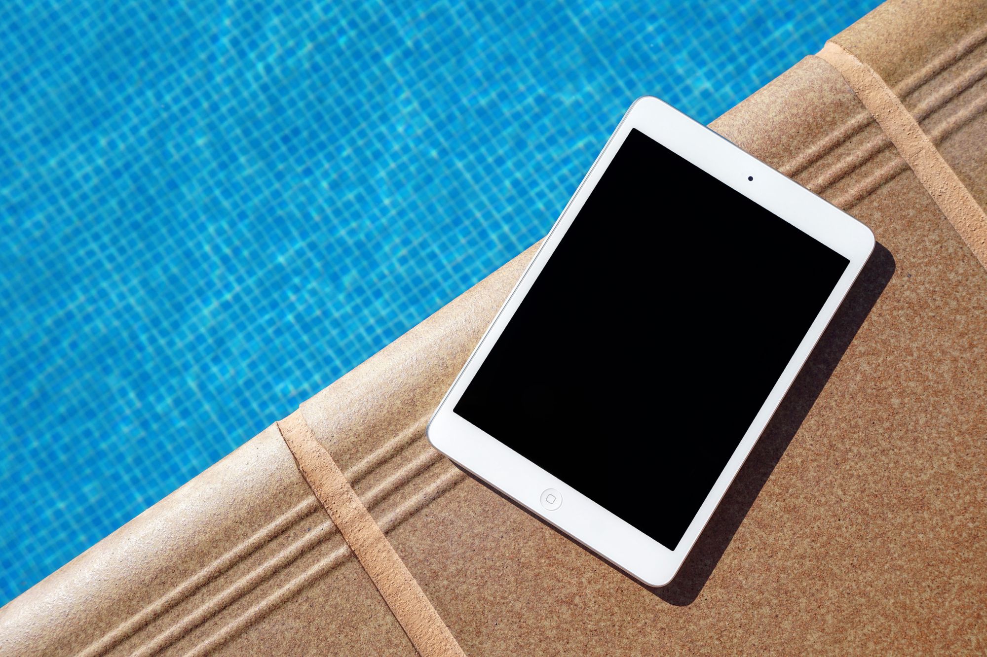 An iPad placed on the edge of a swimming pool