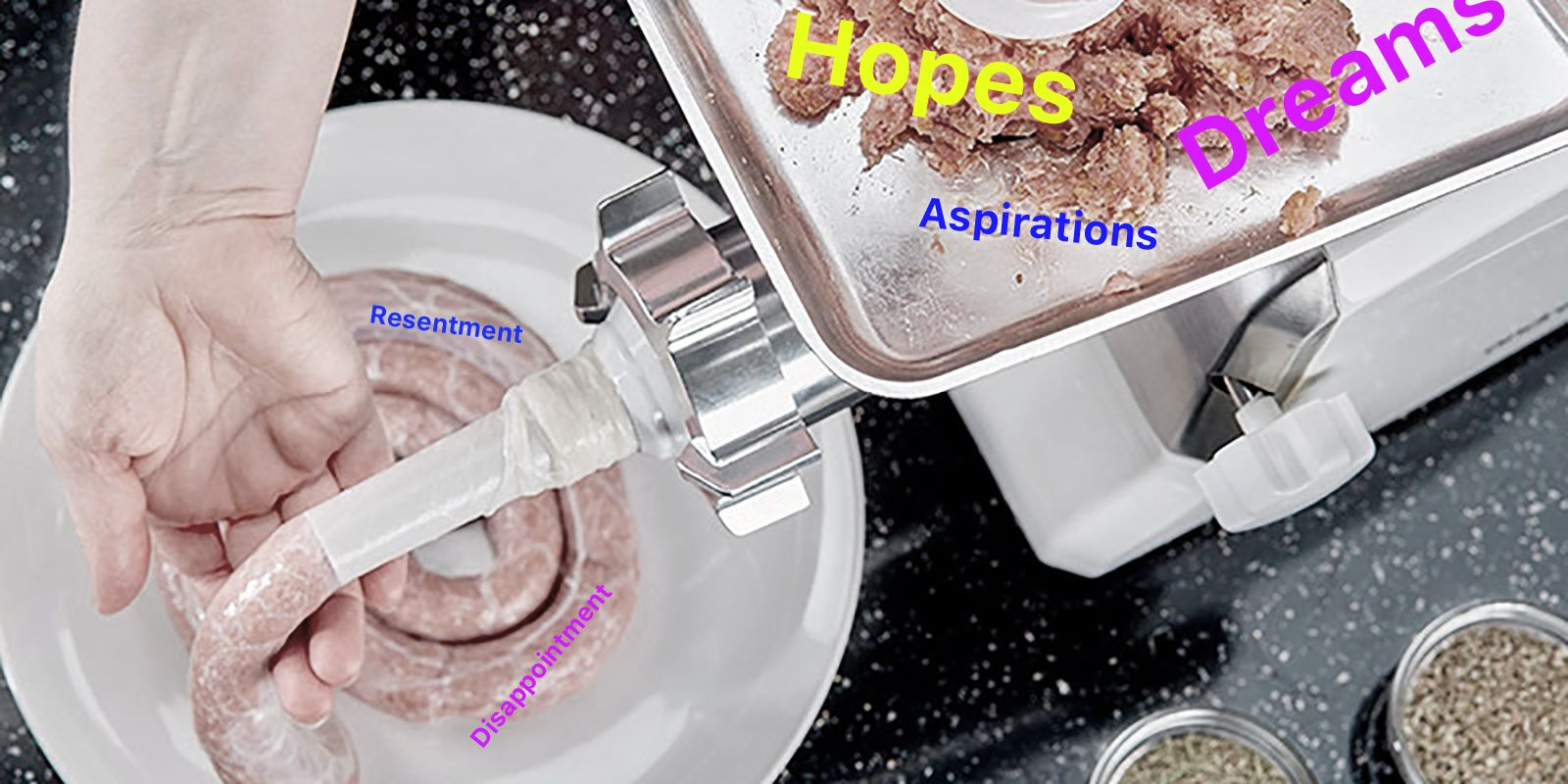 A sausage grinder, with the words 'hopes, dreams and aspirations' over the meat, and the words 'resentment and disappointment' over the sausage.