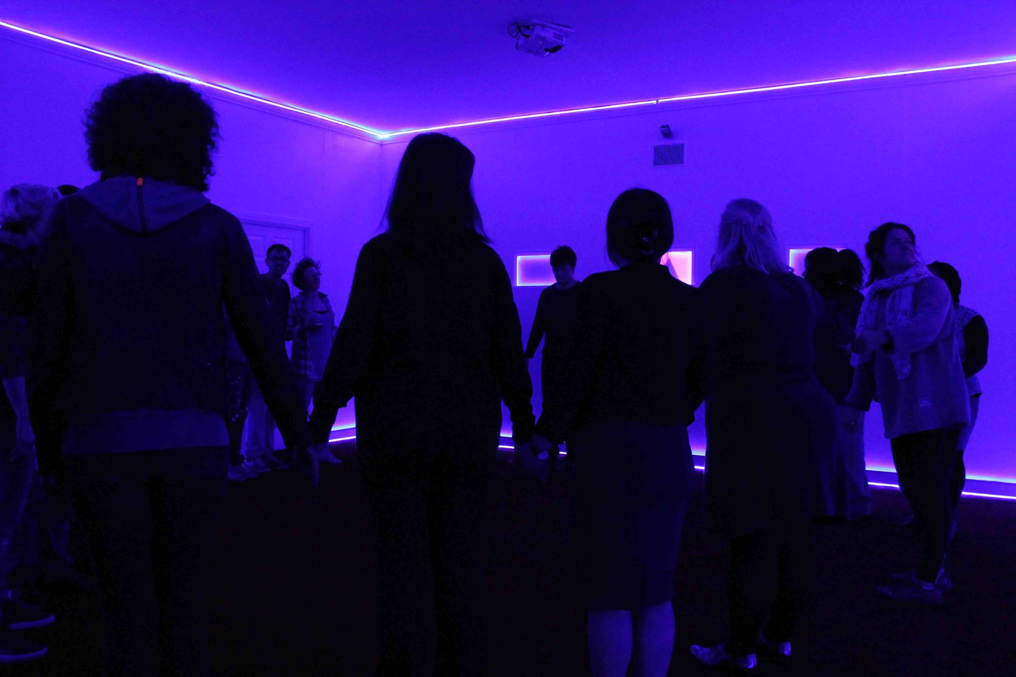 In Invisible Treasure, which was a piece of theatre without actors, we thought about how to communicate with audiences. Here, a group of people arrange themselves in a circle in a semi-darkened room. One person checks a screen behind them which contains visual instructions.