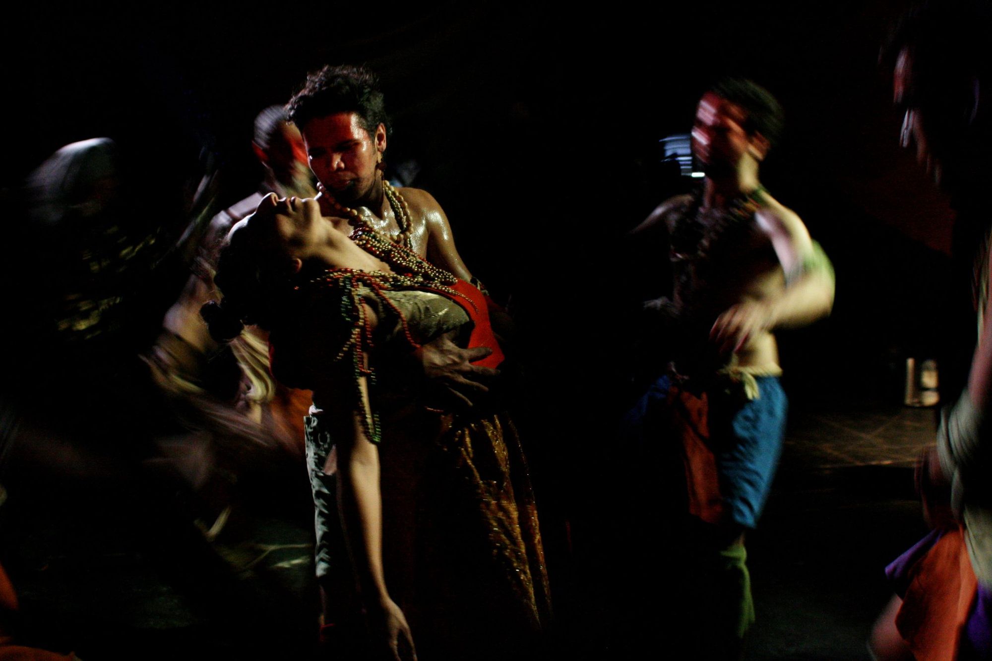 Four blurred images of people dancing. They are shirtless and have their faces painted. One of them holds a fifth person who looks like they have fainted. This is an image from immersive theatre pioneers ZU-UK's production of Hotel Medea.a 