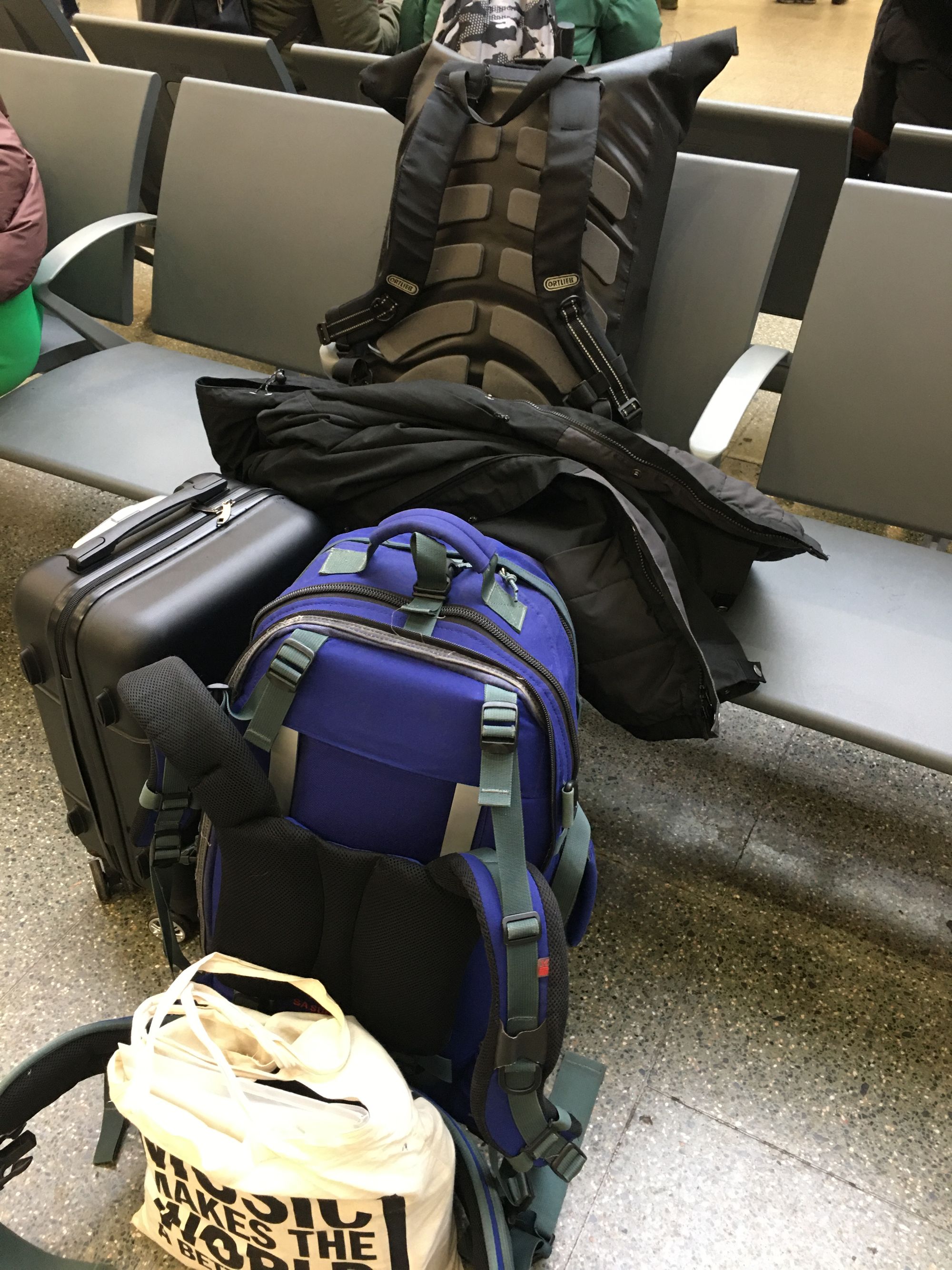 A 30 litre black waterproof bag, a large back-packing style blue rucksack, an executive black wheelie case, and a tote bag.