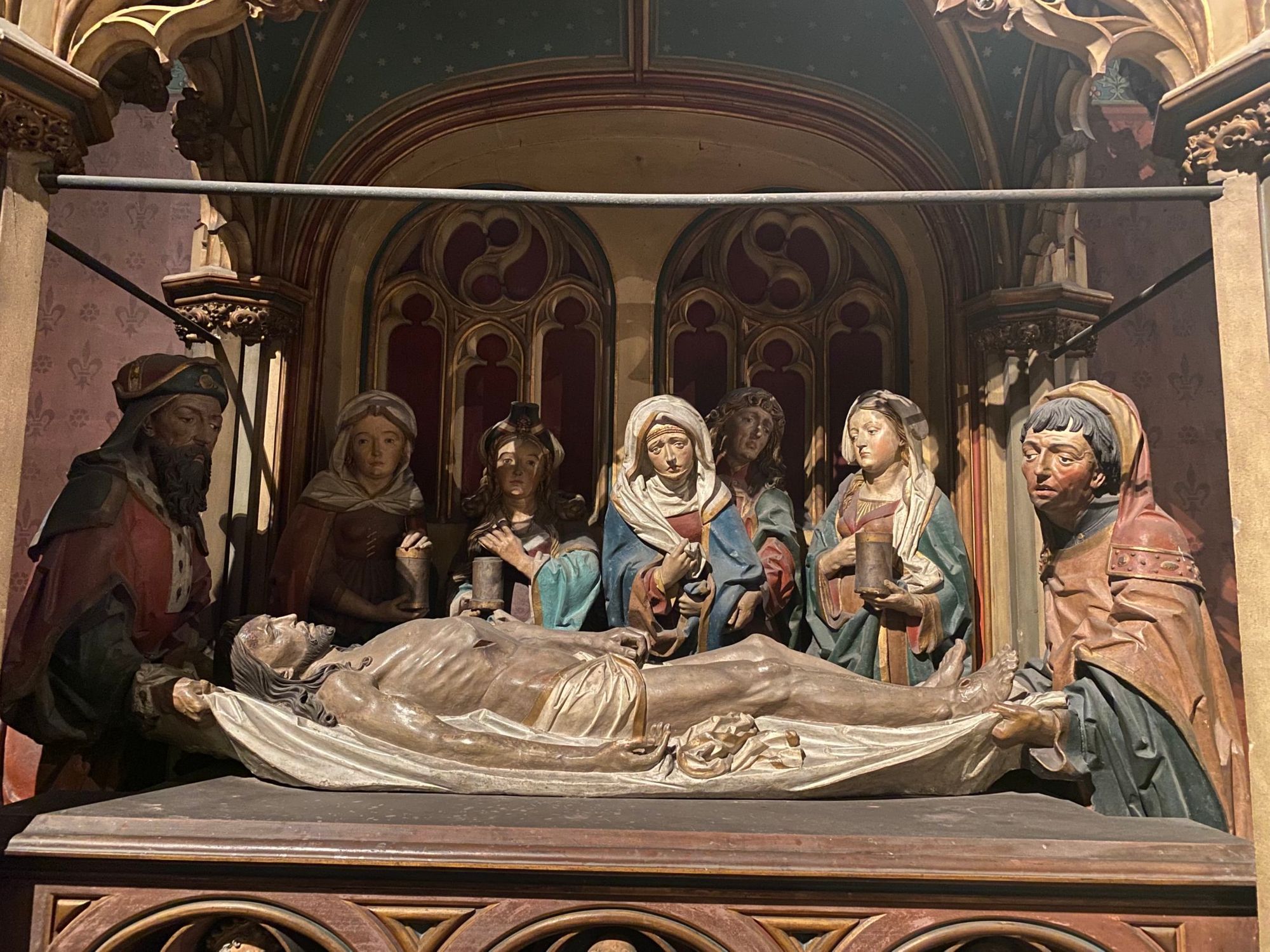 Wooden statues showing Jesus lying dead on a shroud with the Virgin Mary standing beside him and other men and women looking on